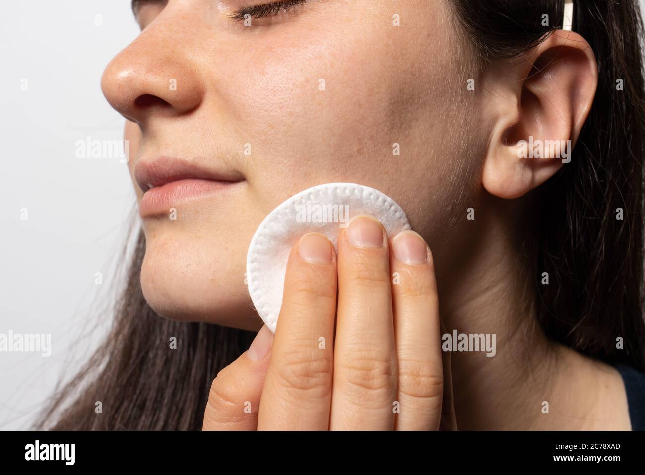 A 30-year-old woman wipes her face with a cotton pad with tonic. Facial skin care. Stock Photo
