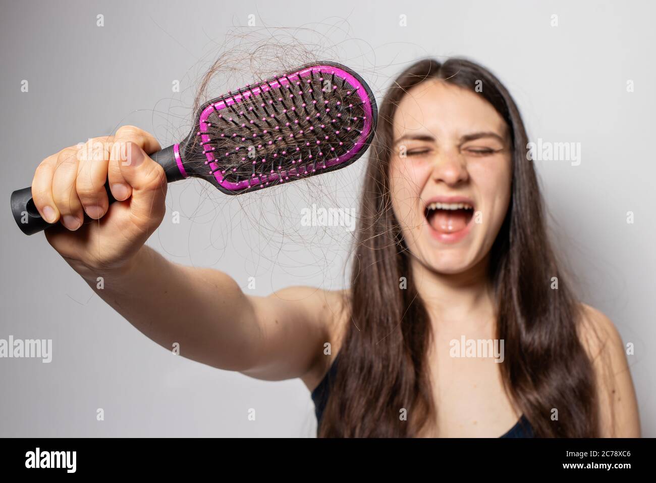 The girl holds a comb for hair with fallen hair. Hair loss, hair care. Stock Photo