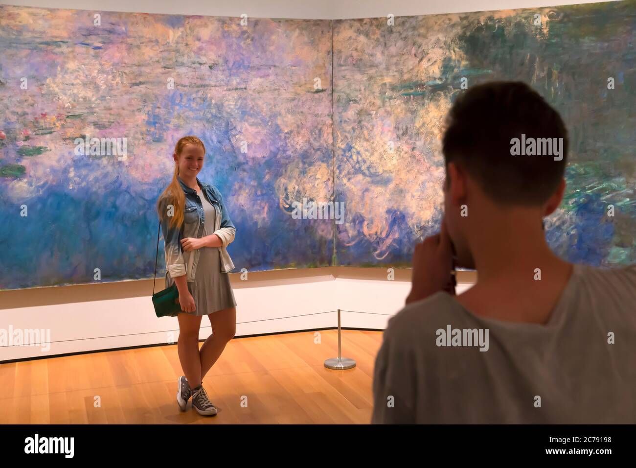Young man taking photo of girlfriend in front of Water Lilies by Claude Monet, circa 1920, MOMA, Stock Photo