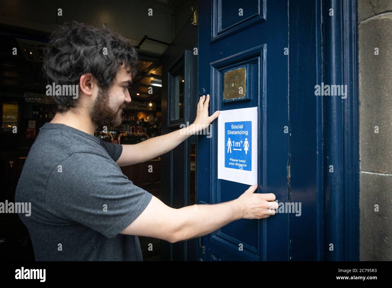 A member of staff places a safety sign on the door of The Scotsman's Lounge pub in Edinburgh as pubs, bars and restaurants across Scotland have opened indoor areas for the first time since March after the lifting of further coronavirus lockdown restrictions. Stock Photo