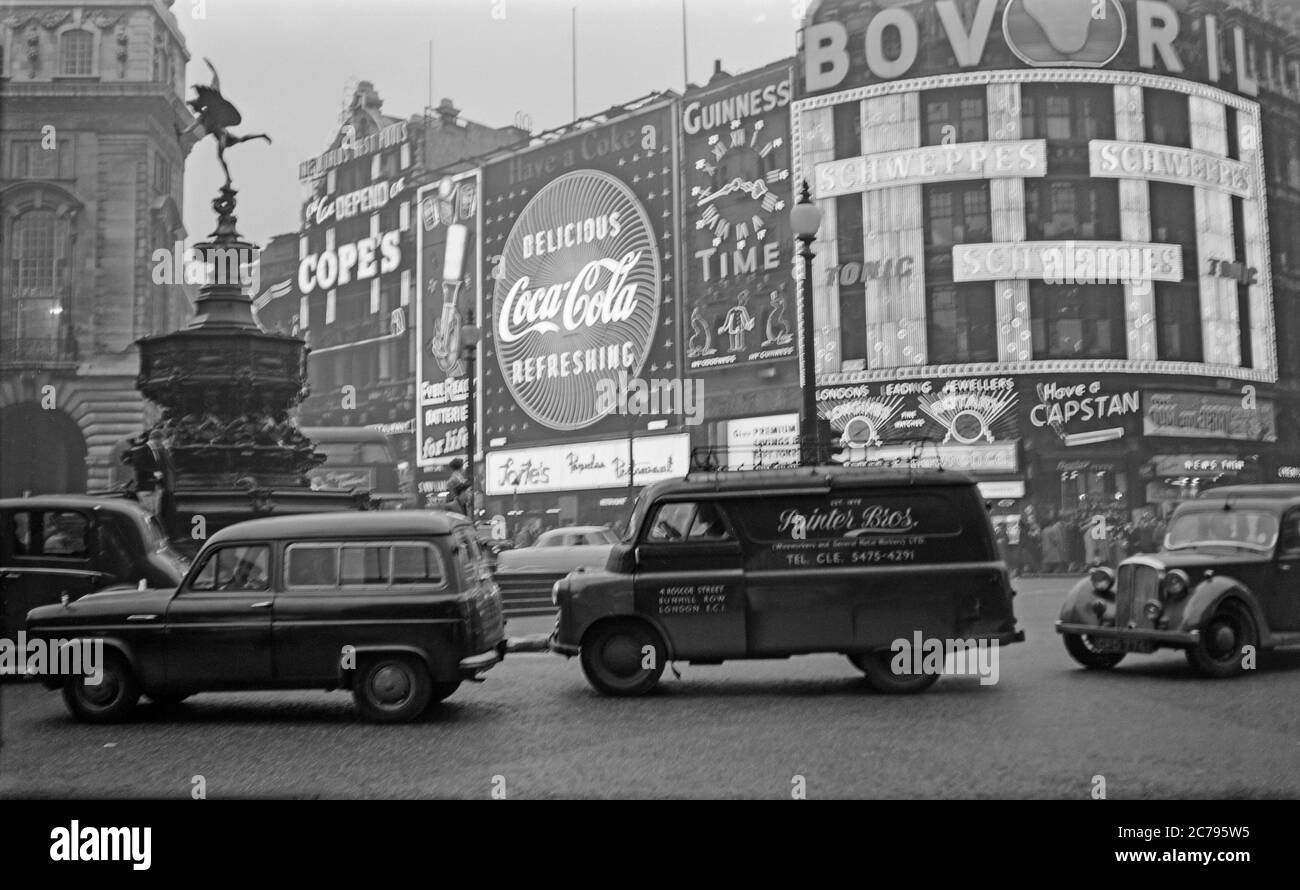 Vintage 1950s photograph of Piccadilly Circus in London, England. Shows the neon advertising signs of the era, including Coca Cola, Bovril, Guinness, Ever Ready. Also cars and vans of the era. Stock Photo