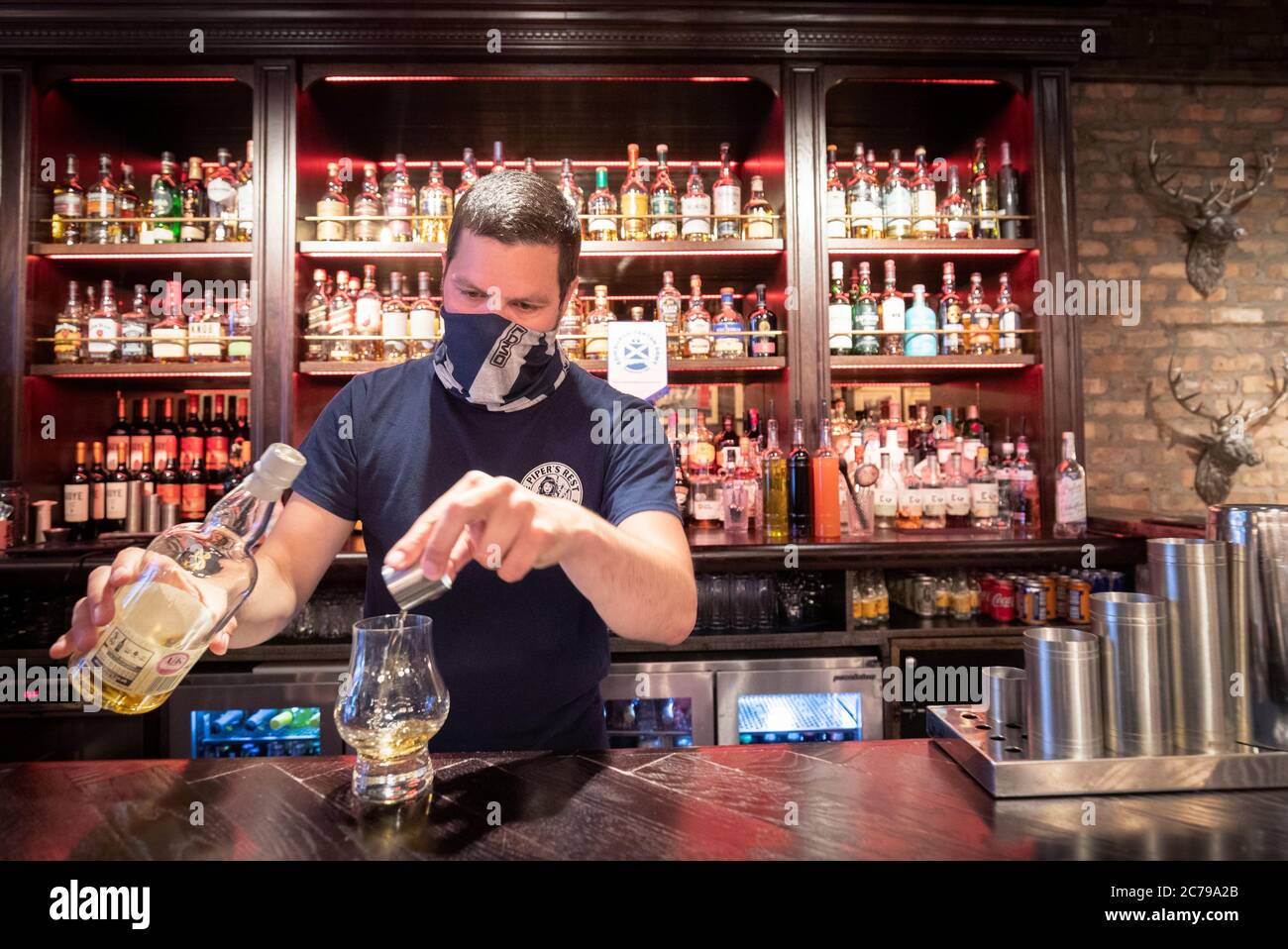 Barman Dejah Hajdukovic serves a whisky at The Piper's Rest pub in Edinburgh as pubs, bars and
