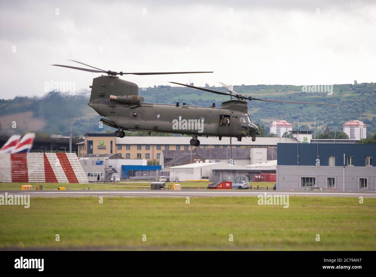 Glasgow, Scotland, UK. 15th July, 2020. Pictured: Royal Air Force Chinook Helicopters seen on the tarmac and taking off from Glasgow International Airport. One of the helicopters had gone ‘technical' with an engine problem and a spare part has been flown in by another Chinook aircraft. A lot of people and plane spotters were seen around the perimeter fence to watch the choppers taking off.  Credit: Colin Fisher/Alamy Live News Stock Photo