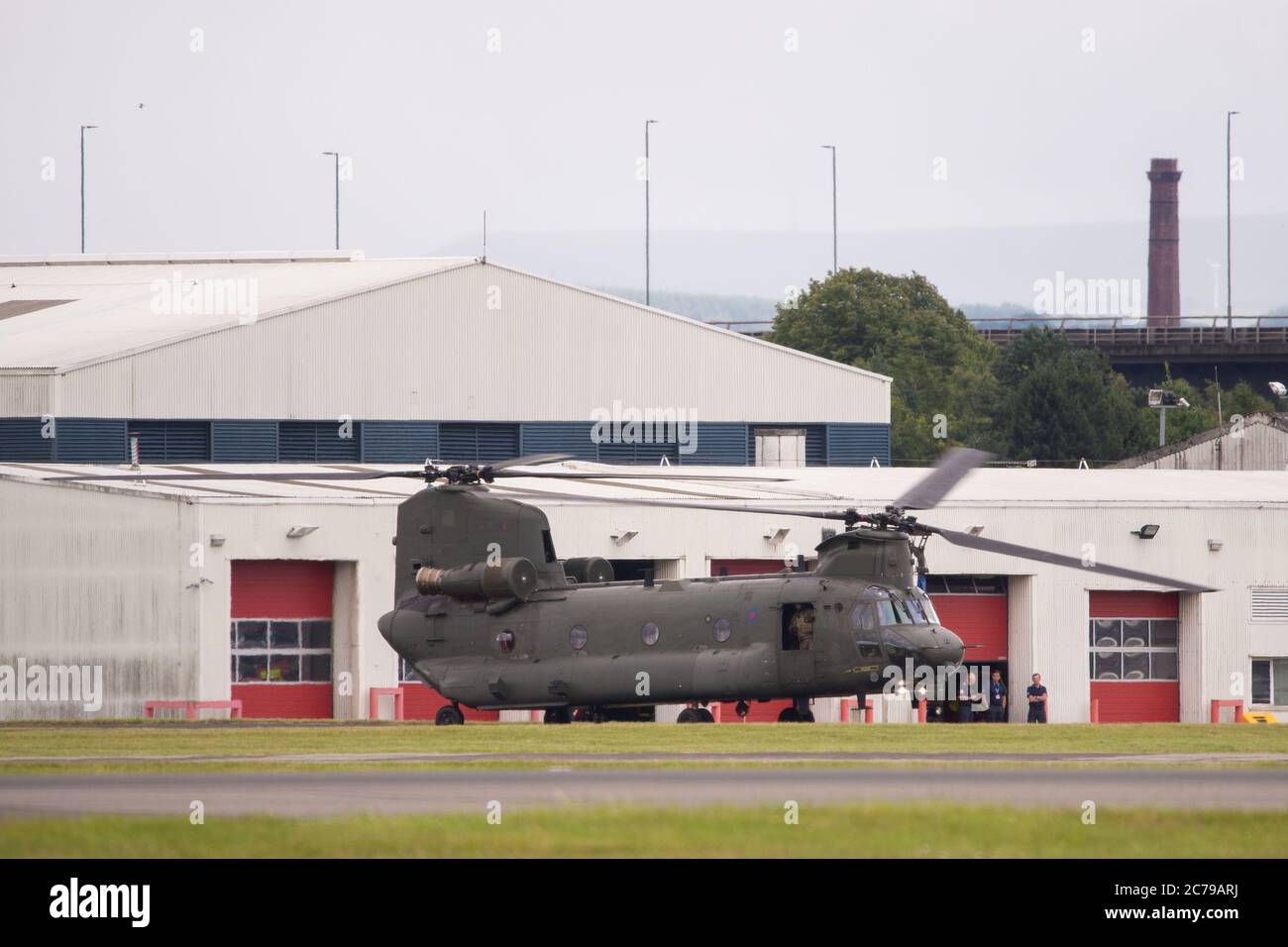 Glasgow, Scotland, UK. 15th July, 2020. Pictured: Royal Air Force Chinook Helicopters seen on the tarmac and taking off from Glasgow International Airport. One of the helicopters had gone ‘technical' with an engine problem and a spare part has been flown in by another Chinook aircraft. A lot of people and plane spotters were seen around the perimeter fence to watch the choppers taking off.  Credit: Colin Fisher/Alamy Live News Stock Photo