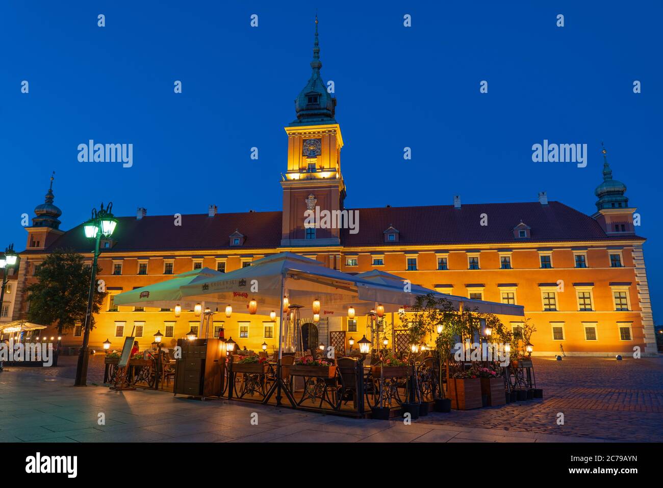 Royal Castle illuminated at night and restaurant outdoor tables in city of Warsaw, Poland Stock Photo