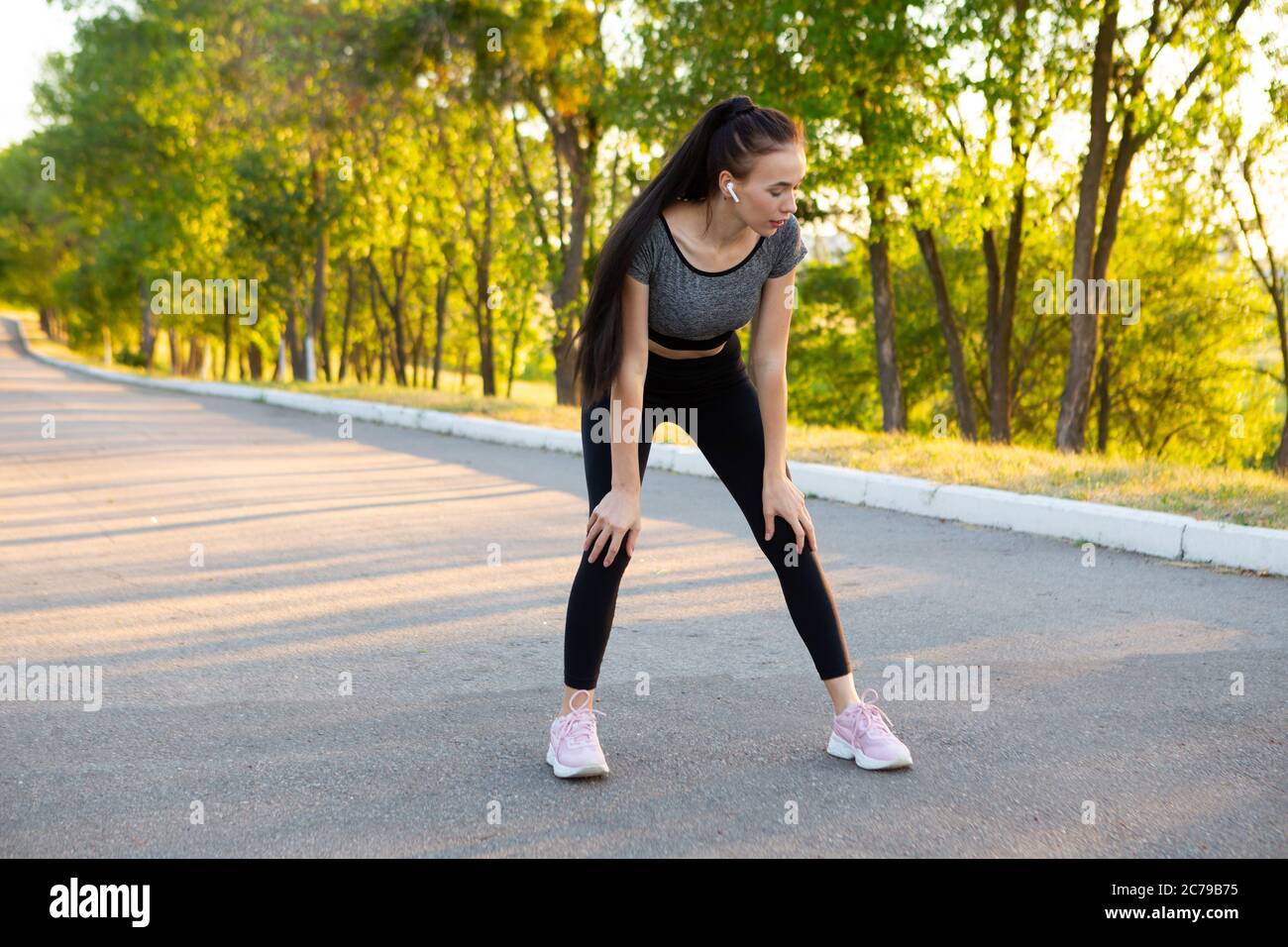 Fitness woman tired jogger breathing after run marathon in park. Stock Photo