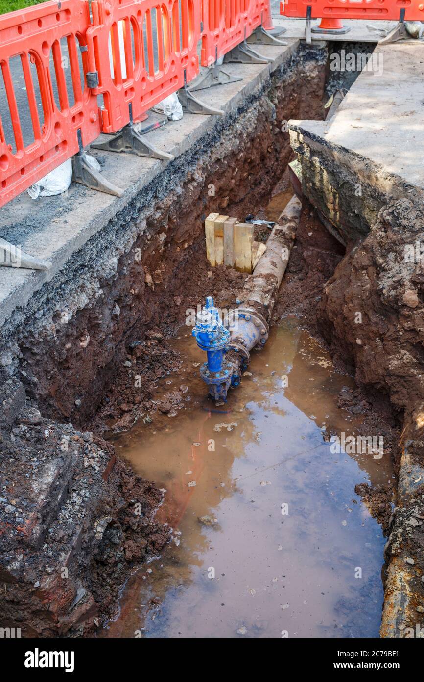 Replacement of a water main pipe and valve by Scottish Water in a deep trench dug in a road, Scotland, UK Stock Photo