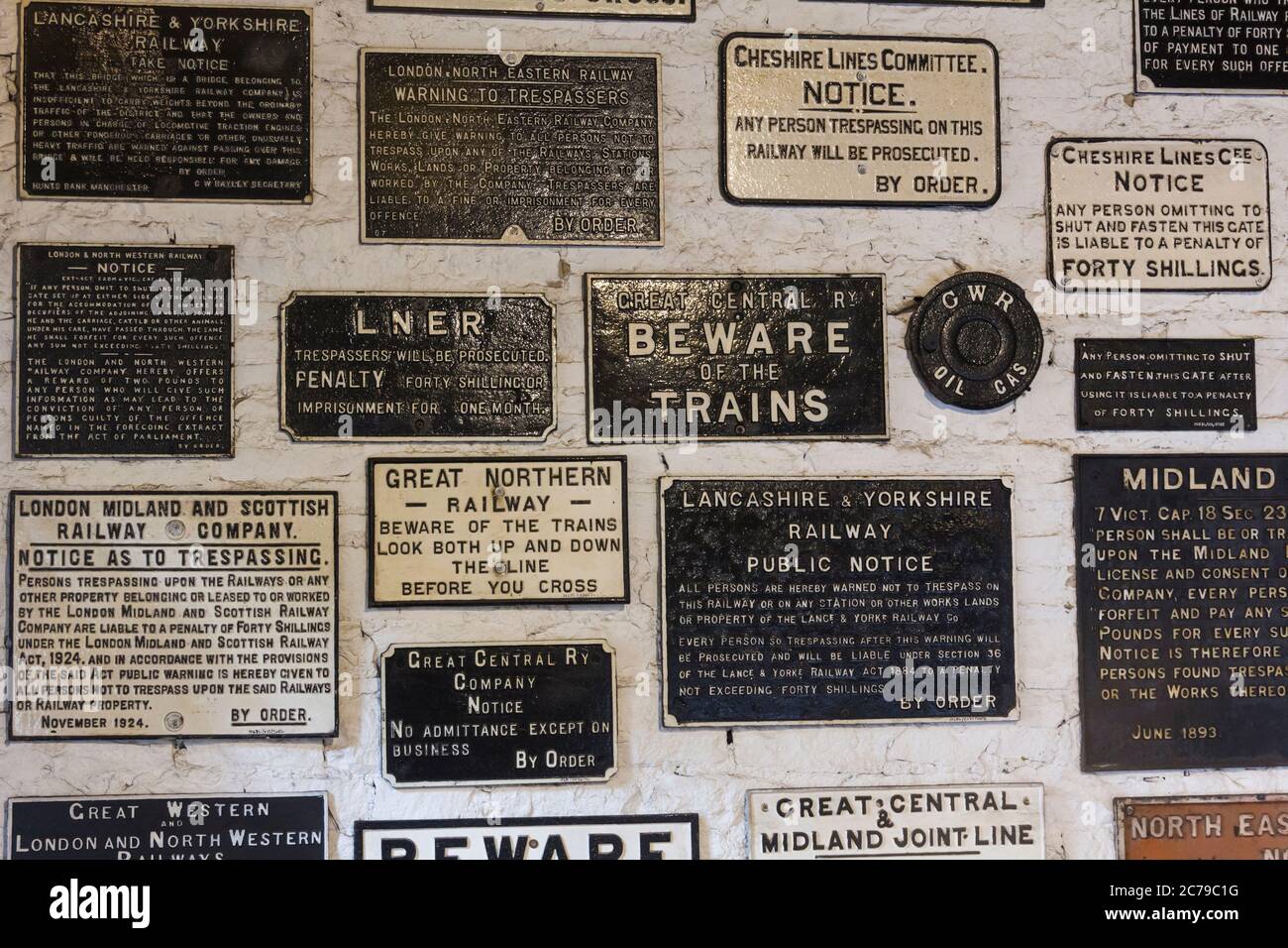 Cast iron railway company 'no trespassing' and other warning signs displayed on a wall at the Ingrow Loco museum, aka 'The Engine Shed'. The museum is Stock Photo