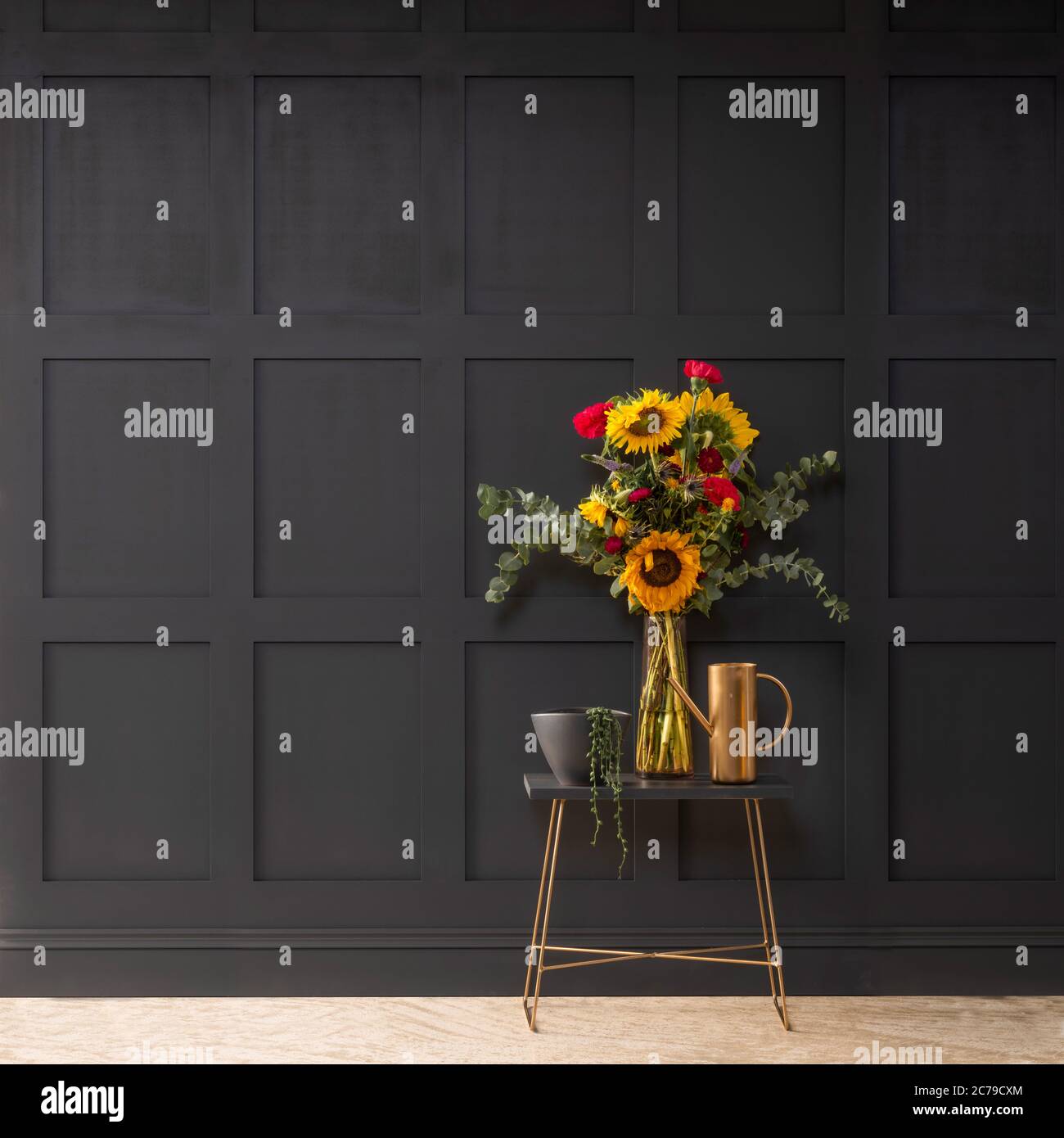 Grey wood panelled wall with small table and vase of flowers Stock Photo
