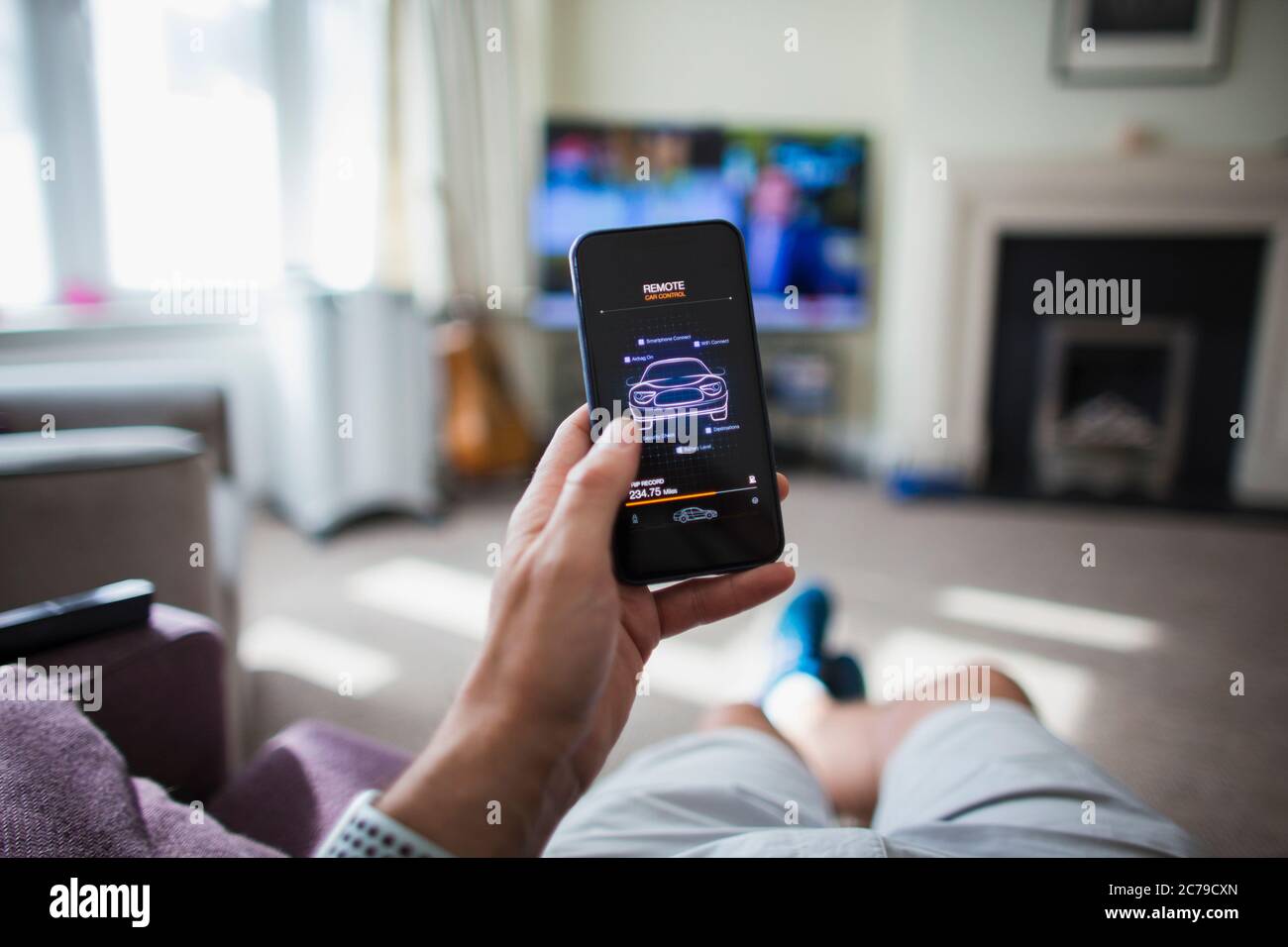 POV Man checking remote car control on smart phone in living room Stock Photo