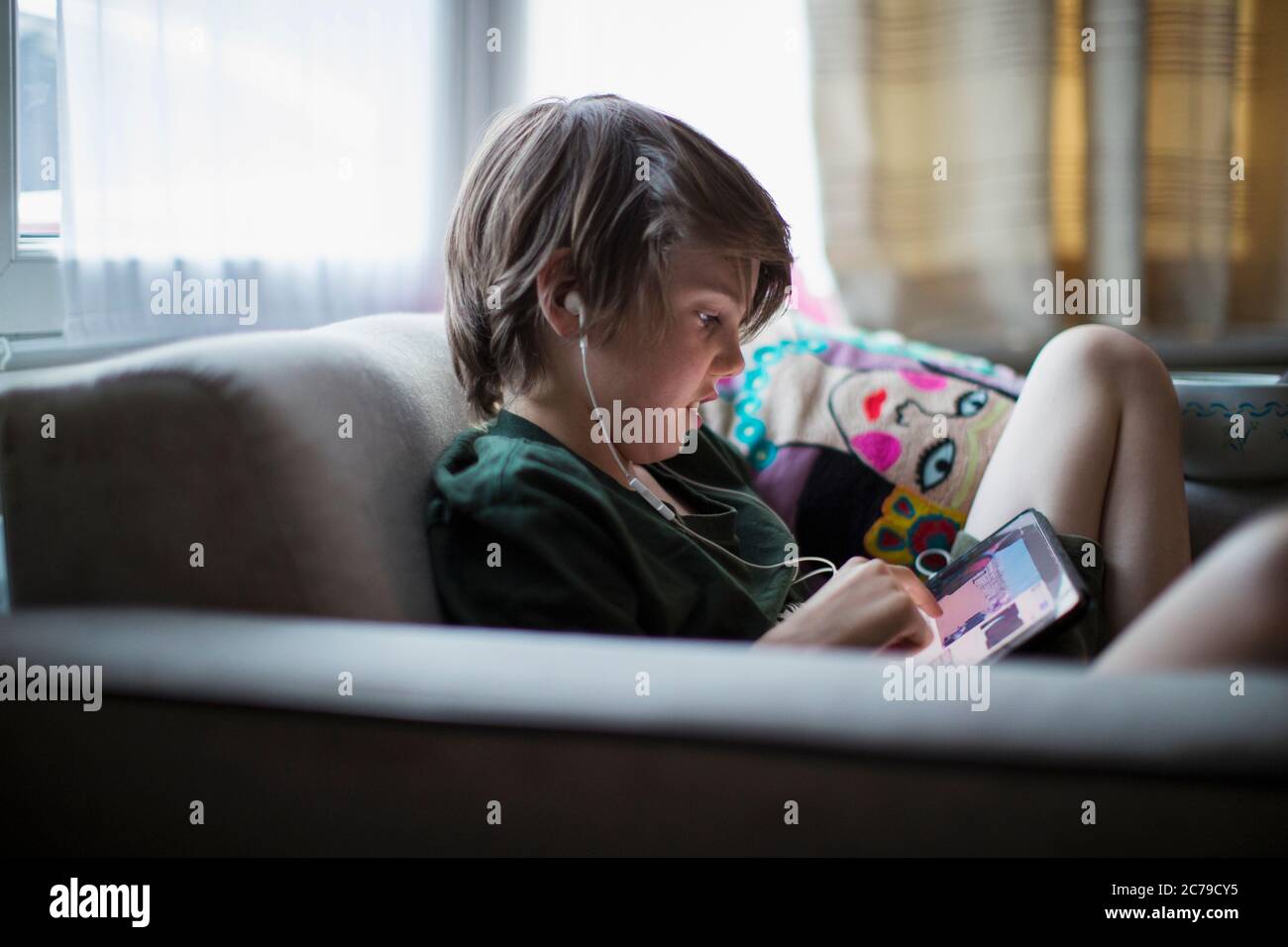 Boy with headphones using digital tablet in living room Stock Photo