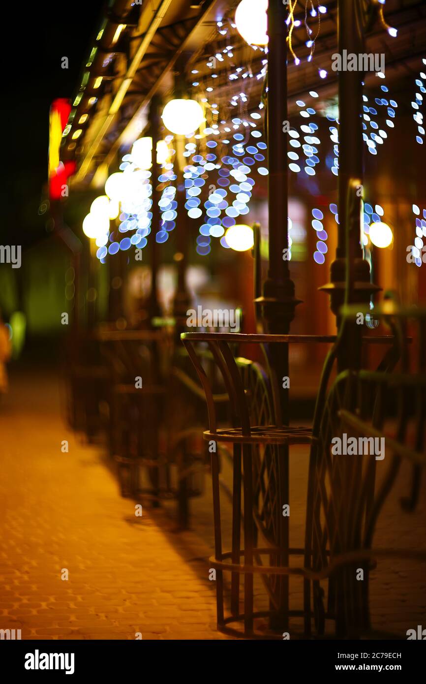 Fences and blurred night lights decorations of the bar on background. Christmas time Stock Photo