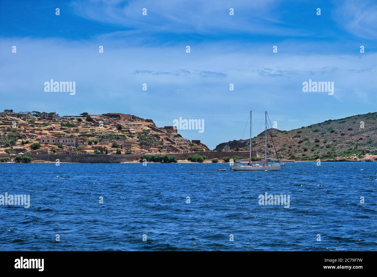 View of Spinalonga island and Venetian fortress, Crete, Greece, and yacht floating on clear summer day Stock Photo