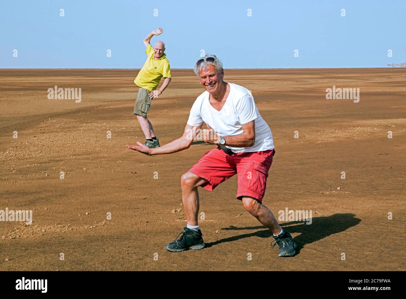 Two tourists playing in sand desert, having fun with perspective in the Danakil depression, Afar Triangle / Afar Depression, Ethiopia, Africa Stock Photo