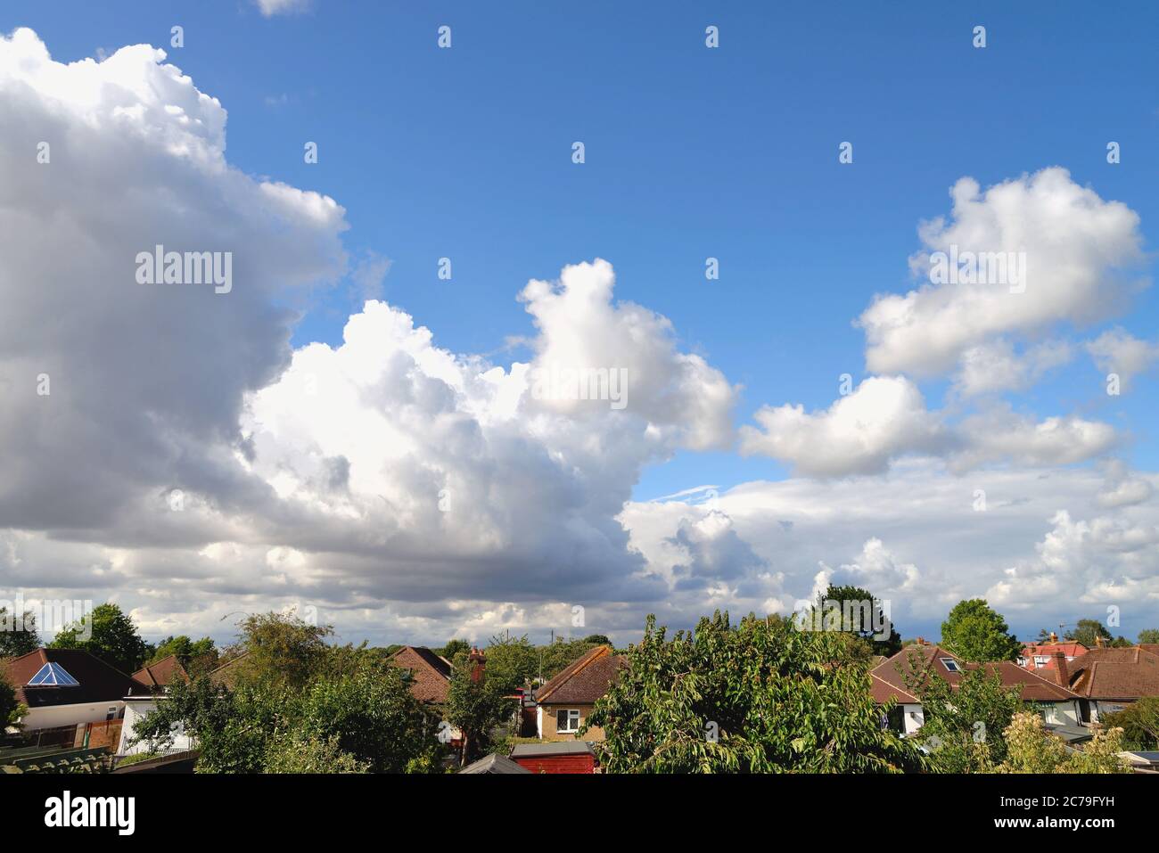 Dramatic cumulus cloud formation forming over rooftops Stock Photo