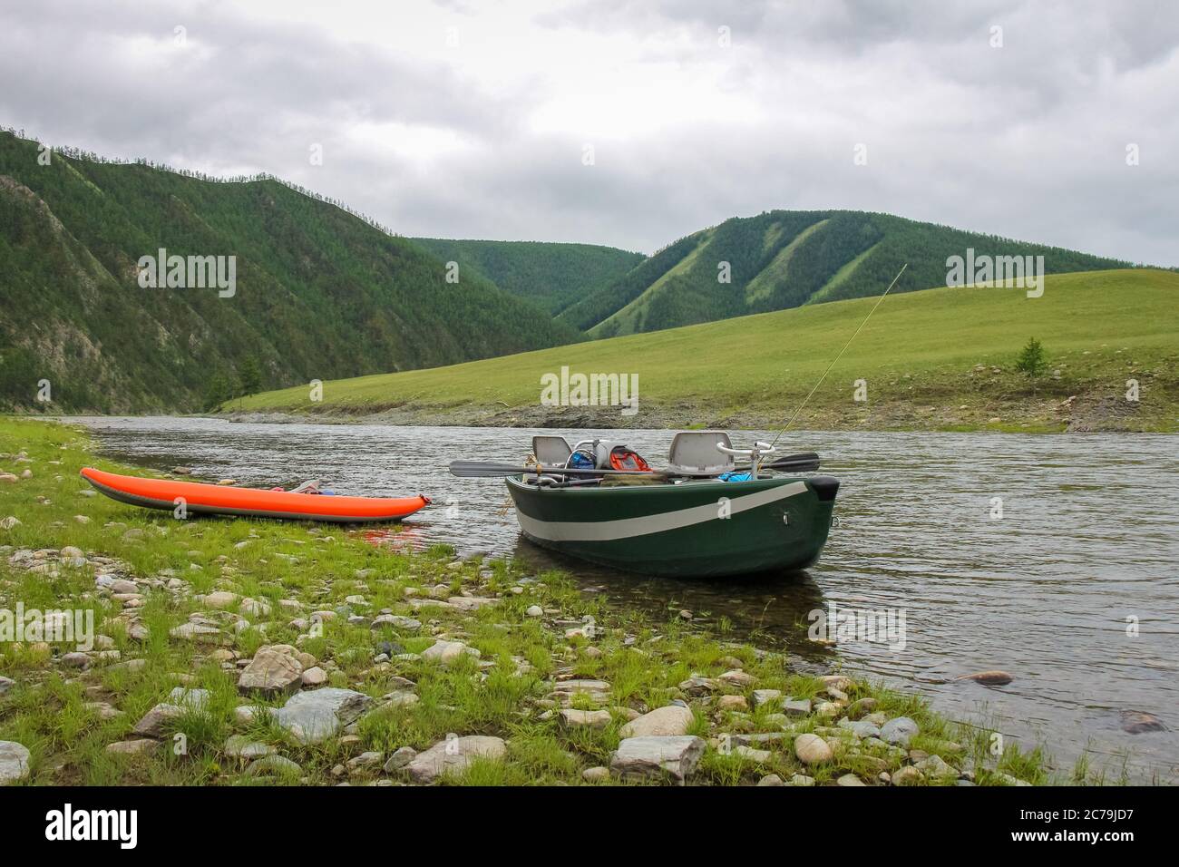 A fishing raft and kayak anchored on the grass bank of a Mongolian ...