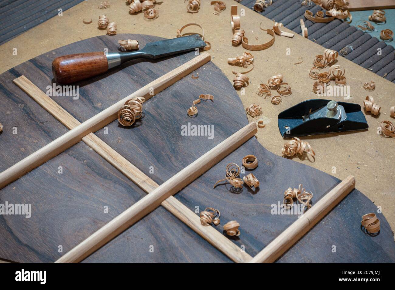 Luthier workbench with tools and back piece of an acoustic guitar under