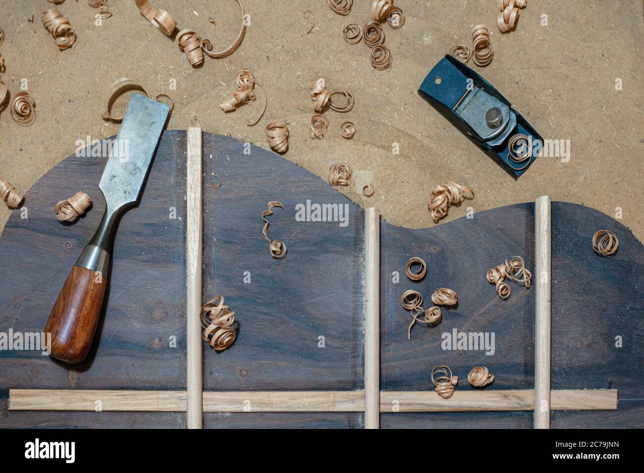 Luthier workbench with tools and back piece of an acoustic guitar under