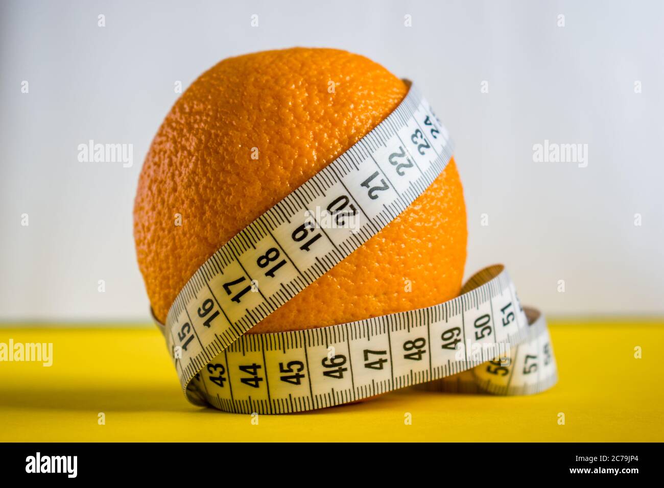 Orange with tape measure on white and yellow background Stock Photo - Alamy