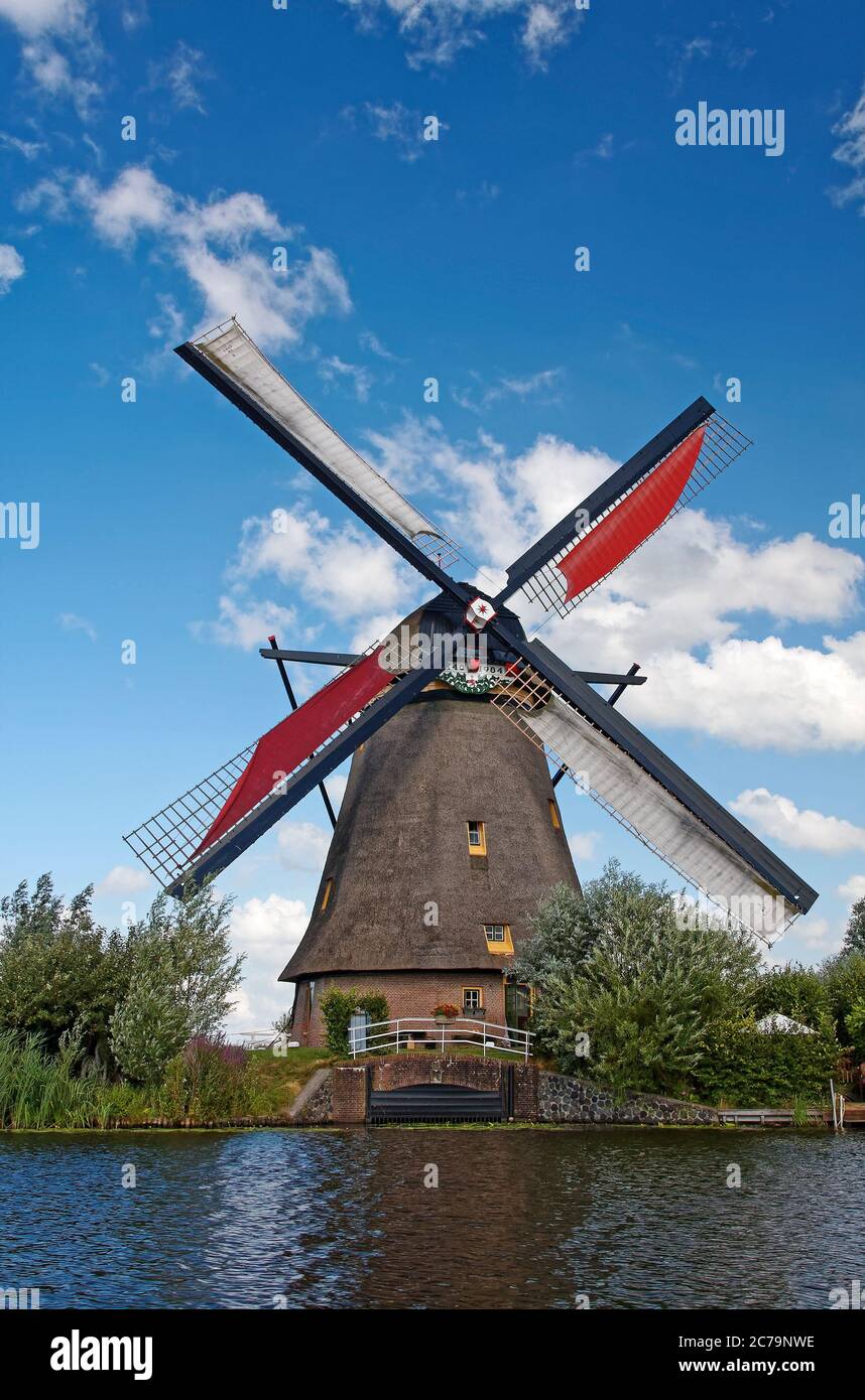 windmill, circa 1740, rebuilt 1984, canal, red canvas on 2 sails, water control gate, UNESCO World Heritage Site, historic, old, Overwaard mill, cover Stock Photo