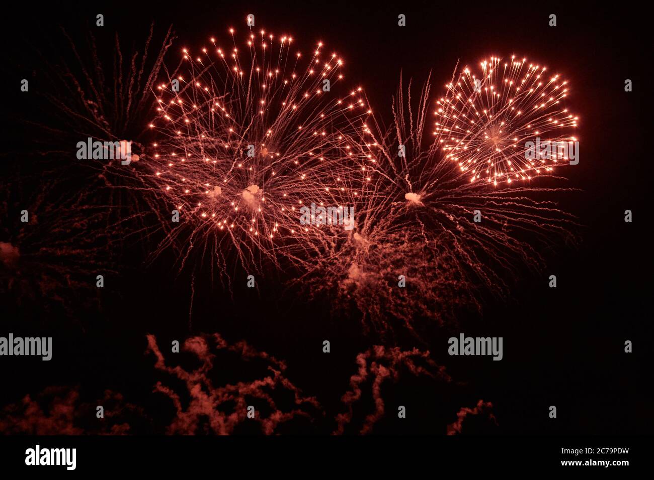 Holiday Fireworks with bright flashes and sparks of different colors in the night sky Stock Photo