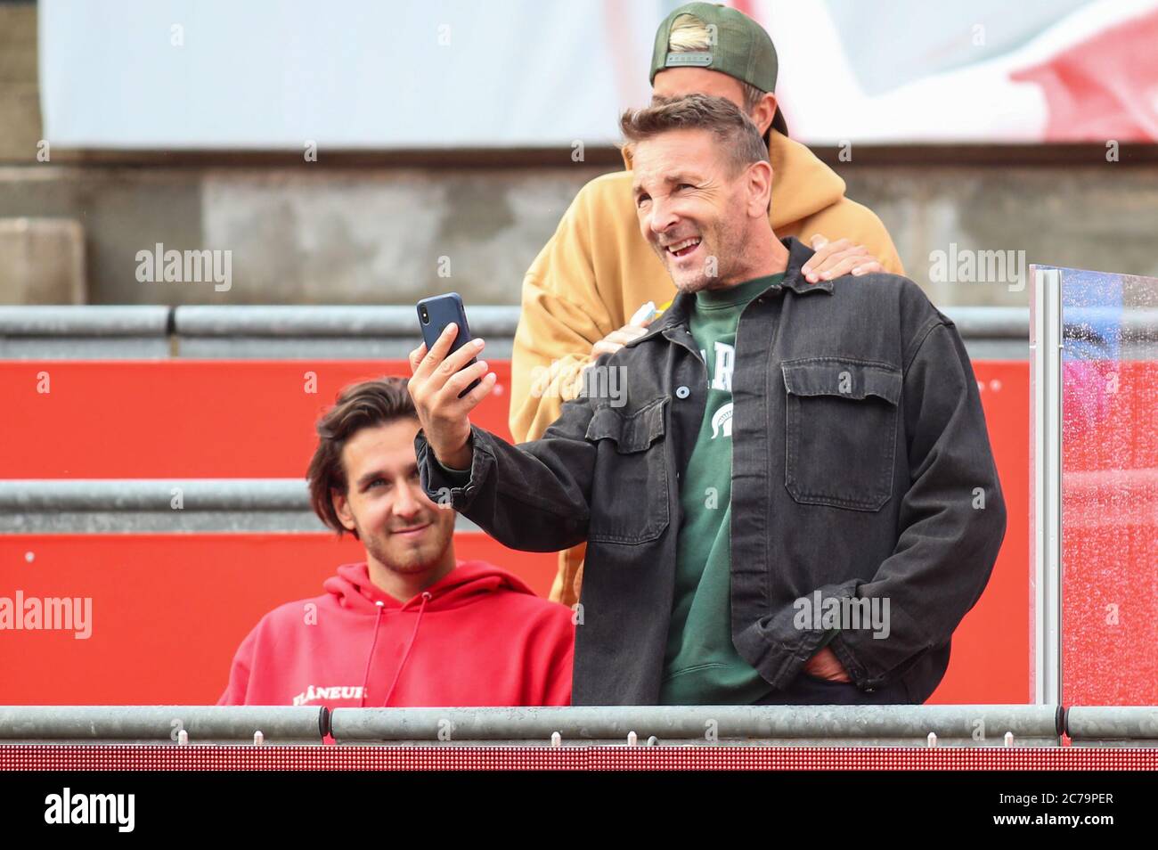 Berlin, Germany. 15th July, 2020. Tennis: Invitational tournament 'bett1aces' for ladies and gentlemen at the Steffi Graf Stadium. Men, singles, final, Berrettini (Italy) - Thiem (Austria). Mark Keller, actor and tennis player, stands laughing with a smartphone on the grandstand. Credit: Andreas Gora/dpa/Alamy Live News Stock Photo