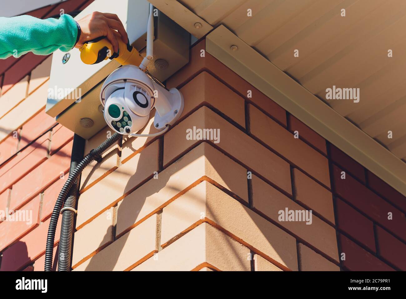 technician female setup cctv camera on wall. Stock Photo