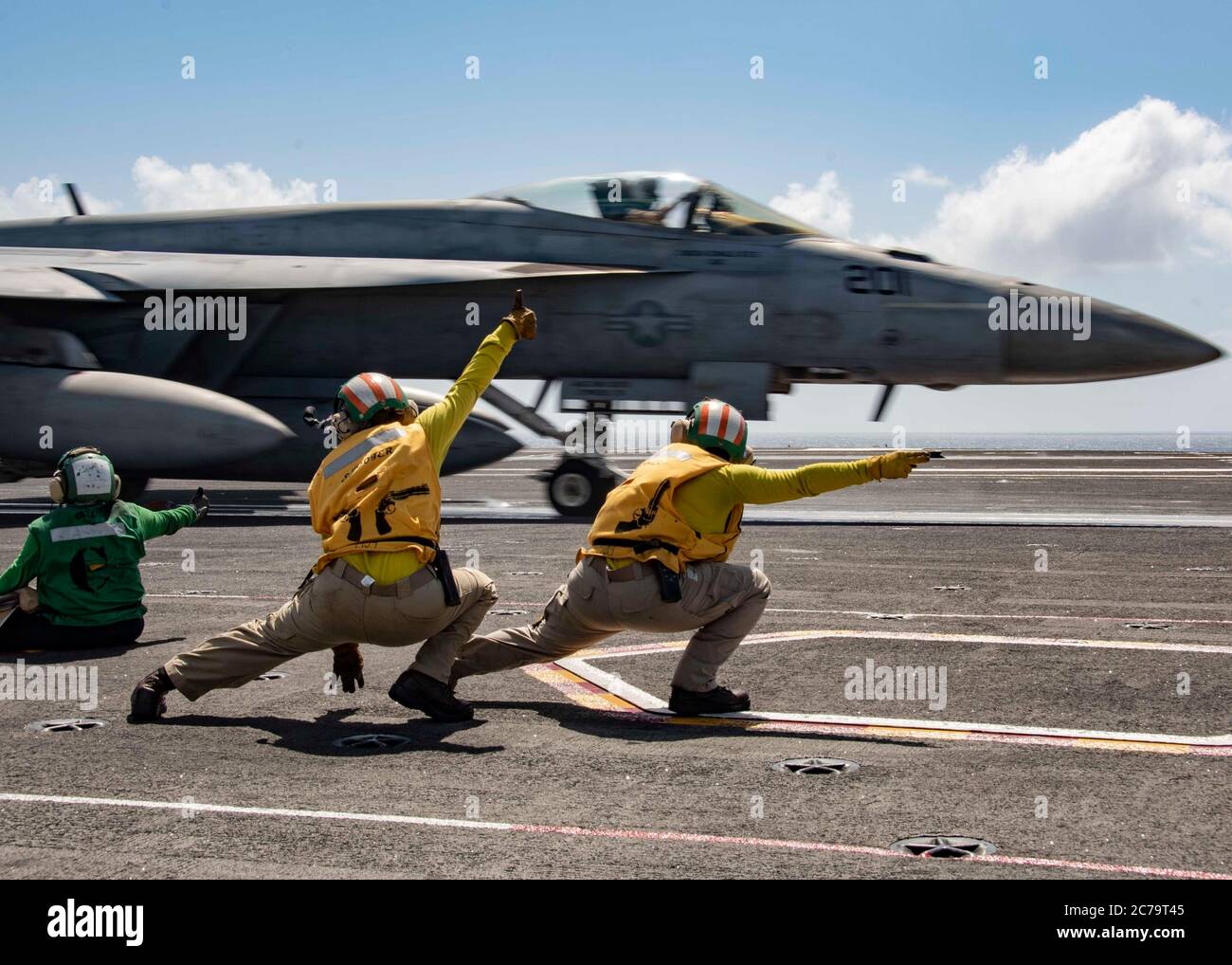 U.S. Navy deck crew signals a F/A-18E Super Hornet fighter aircraft, attached to Royal Maces of Strike Fighter Squadron 27, for launch on the flight deck of the Nimitz-class aircraft carrier USS Ronald Reagan July 14, 2020 underway in the . Stock Photo