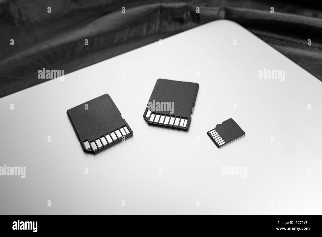 three black memory cards with connectors up on a new gray laptop