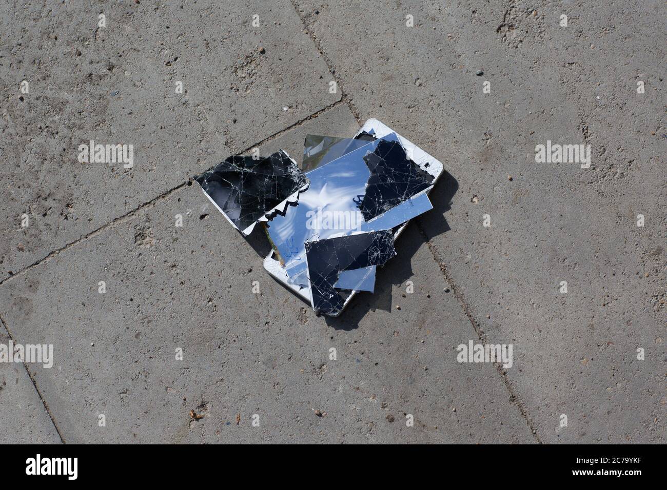 Broken screen mobile phone lies on ground Stock Photo