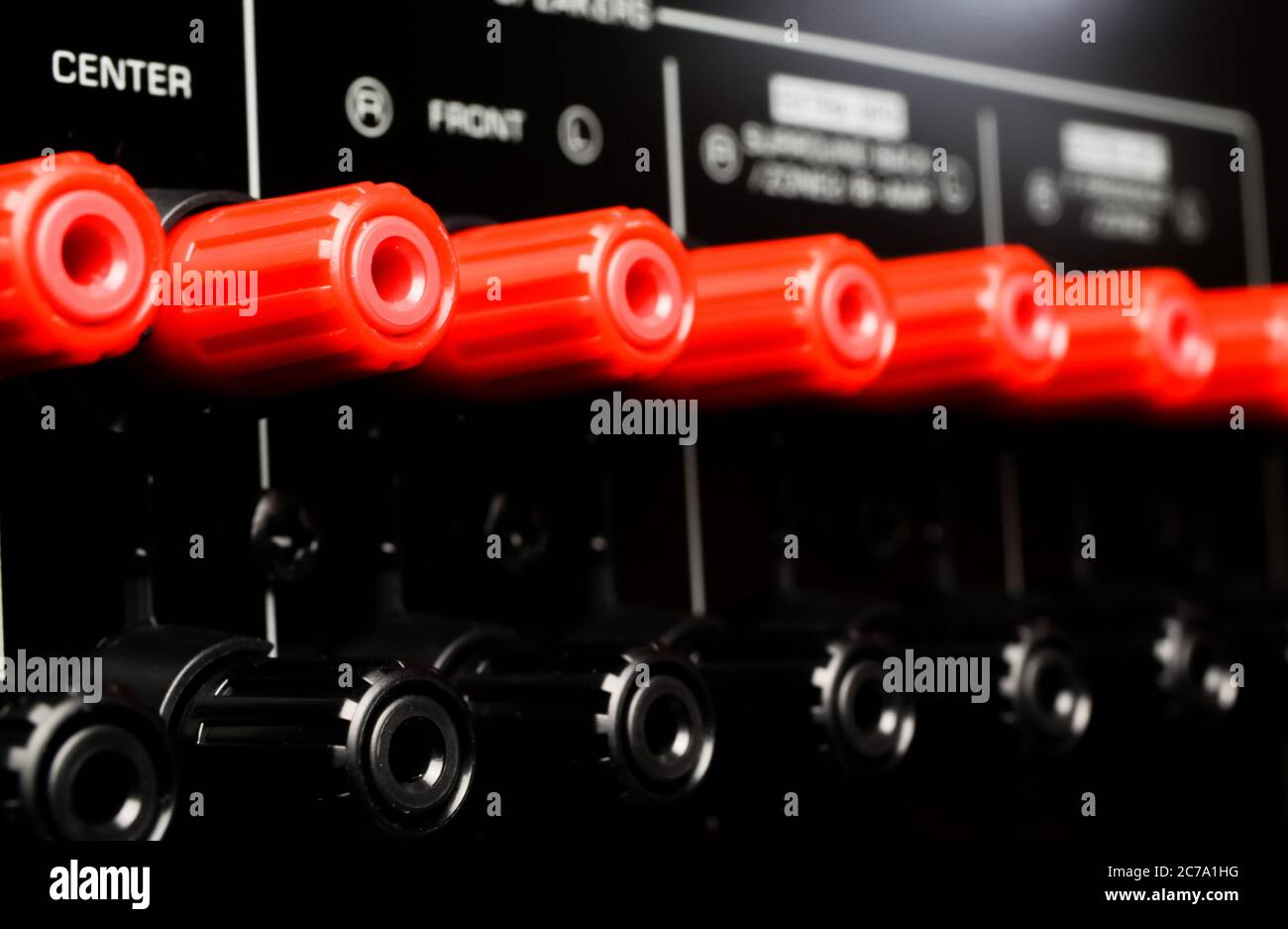 View on isolated red speaker outputs in a row of back side of black dolby surround home cinema receiver Stock Photo