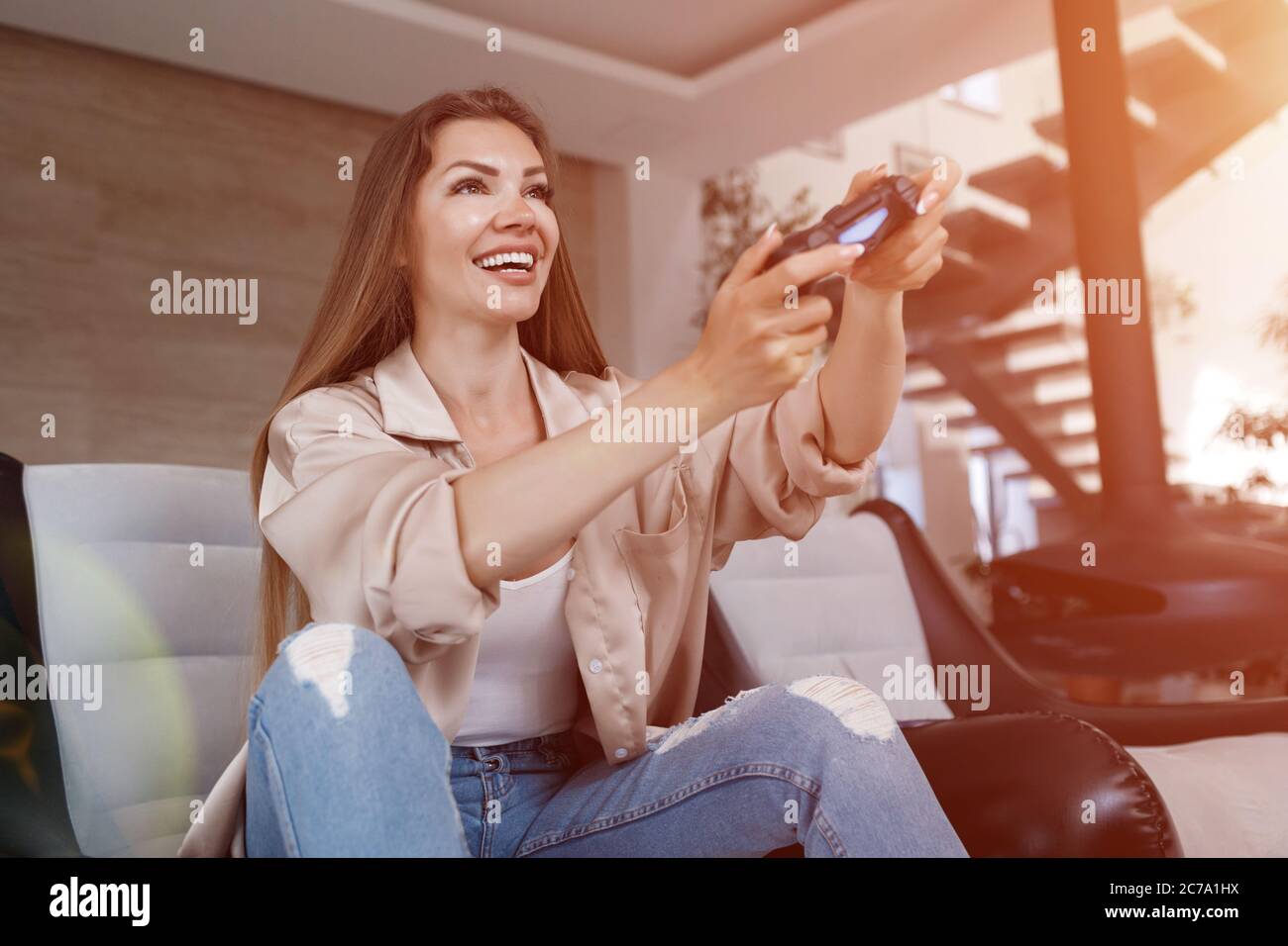 Smiling woman playing video games at home, Soft lights Stock Photo