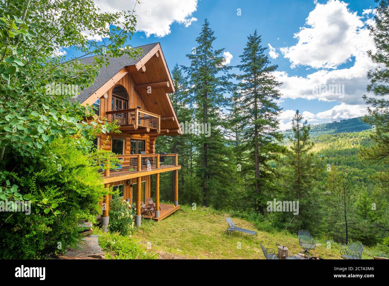 An upscale rural log home on a hillside in the mountains near Sandpoint, Idaho, USA, during summer. Stock Photo