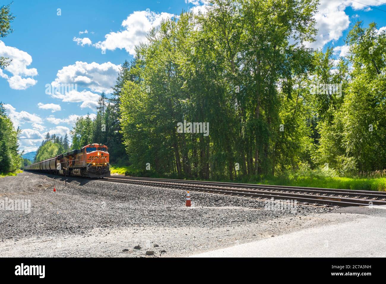 A train locomotive moving on the tracks heads towards an intersection in a mountain town in North Idaho, USA Stock Photo