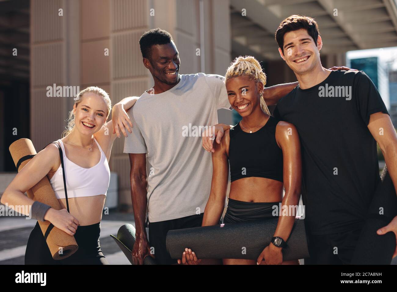Multi-ethnic group of people standing together after exercising session outdoors. Men and women  in sportswear standing together looking at camera and Stock Photo