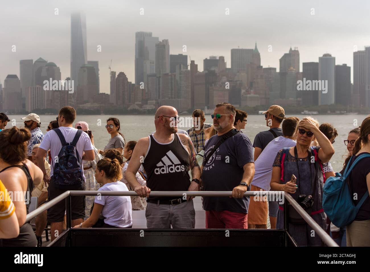 New York City, NY, USA - July 19, 2019: Tourists conversing on a boat with Manhattan skyline behind Stock Photo