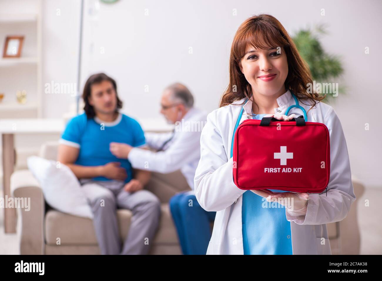 Two doctors visiting sick man at home Stock Photo