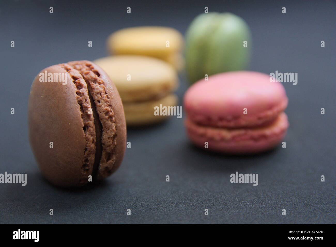 Several macarons of various colors on a table with black color texture and copy space Stock Photo