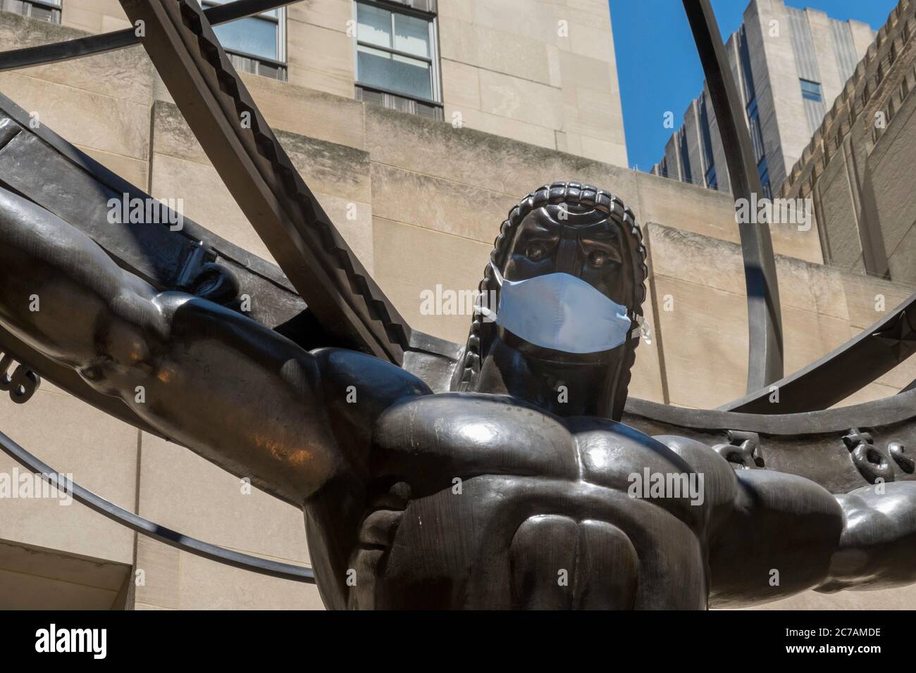 Ancient Greek Titan Atlas Holding the Heavens Bronze Armillary Sphere Sculpture in Rockefeller Center wearing a face mask due to COVID-19, NYC, USA Stock Photo