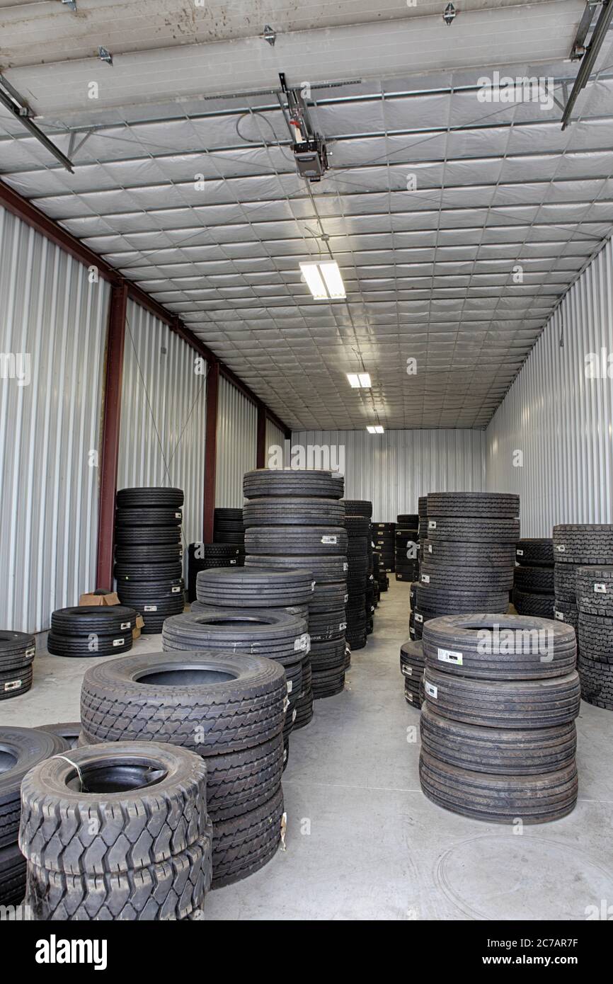 New and used tires stacked in a small warehouse, waiting for installation on trucks. Stock Photo