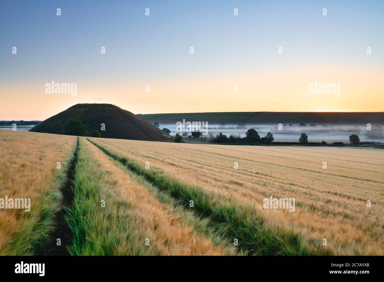 Silbury Hill and mist in the summer at sunrise. Avebury, Wiltshire, England Stock Photo