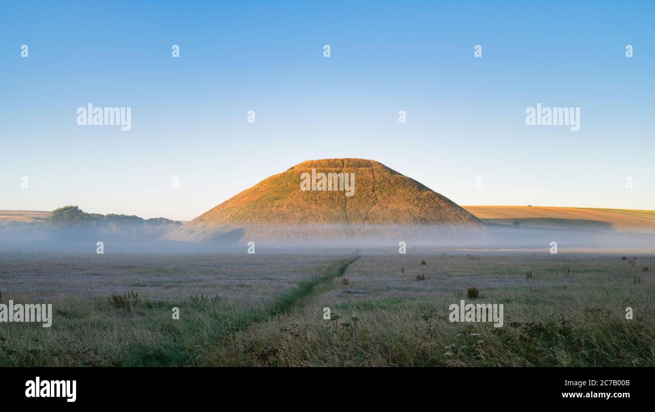 Silbury Hill and mist in the summer at sunrise. Avebury, Wiltshire, England Stock Photo