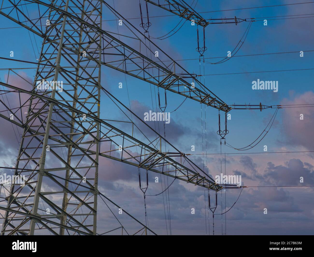Details of a pylon of a high-voltage power line in front of a blue and ...
