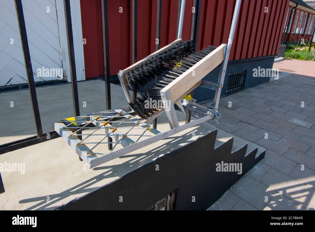 Outside a building at the entranceway, a hardcore metal boot, shoe brush for removing winter snow, ice. In Stockholm, Sweden. Stock Photo