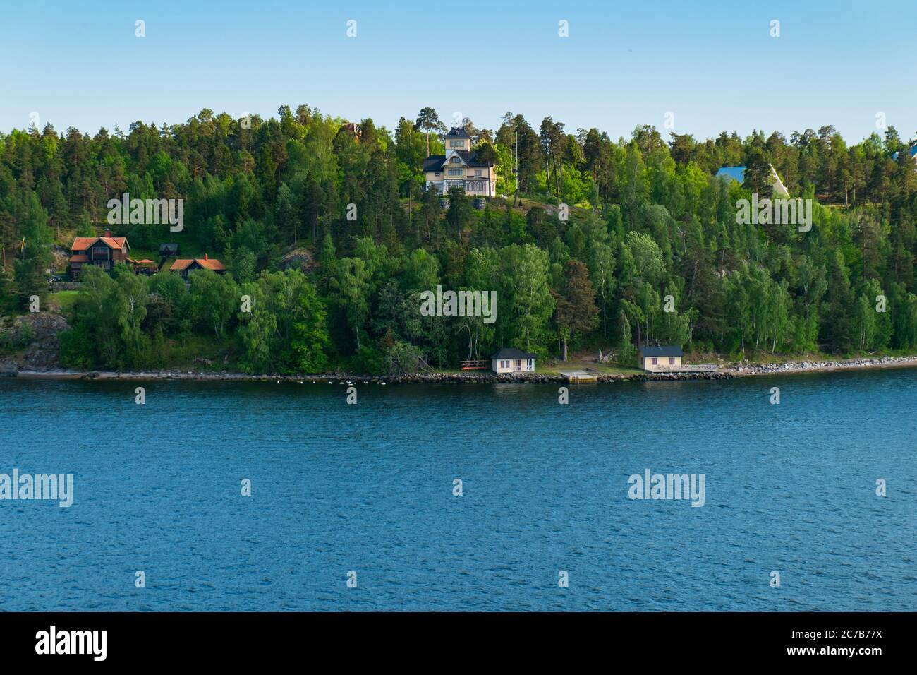 An old Victorian mansion at the top of a hill as the sun sets. Cruising Lake Mälaren near Stockholm, Sweden. Stock Photo
