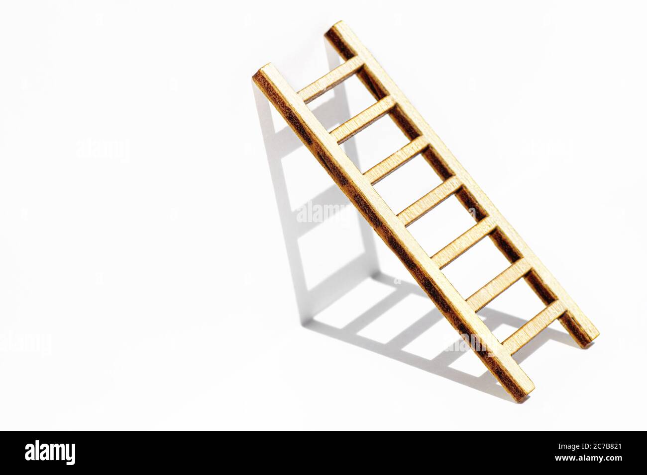 Small wooden ladder leaning against a white wall casting shadows