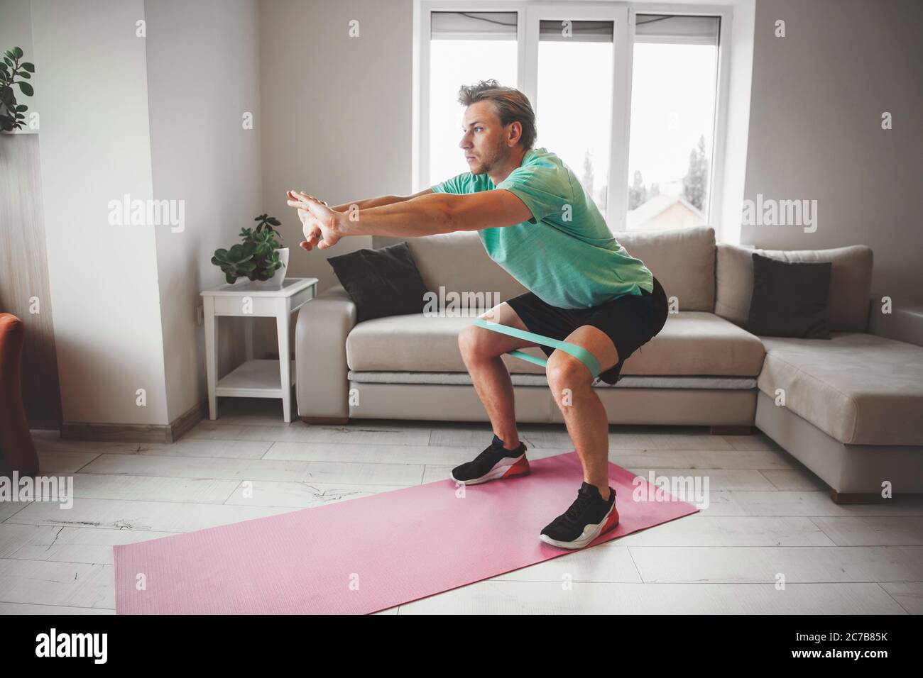 Caucasian man stretching and warming up at home while doing fitness Stock Photo
