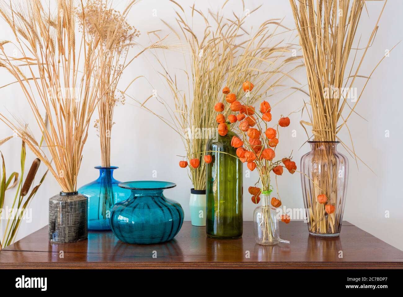 beautiful varied vases with dry plants on an old antique vintage mahogany chest of drawers Stock Photo