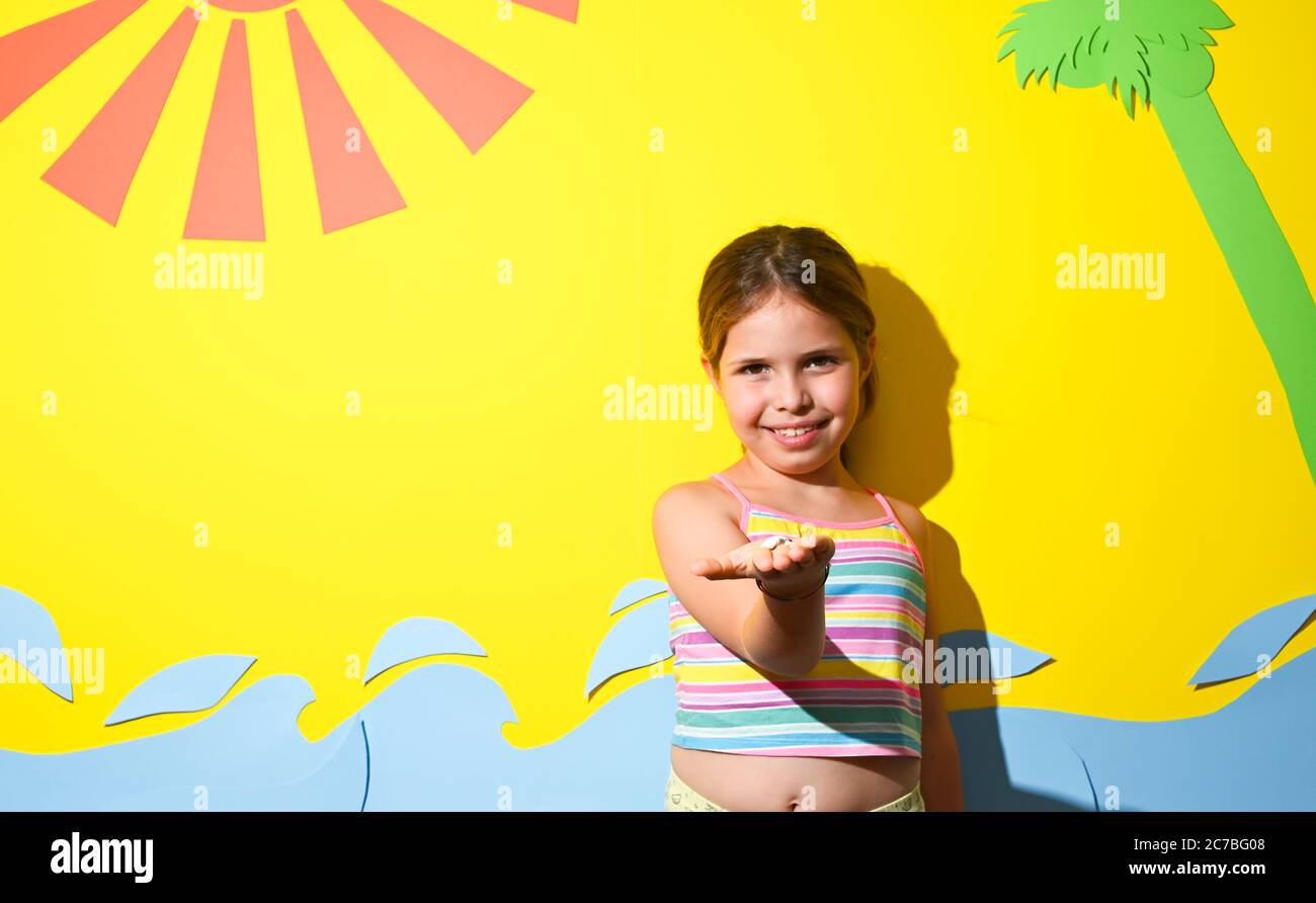 Little girl in a swimsuit on the beach plays, smiles. Child 7 years old