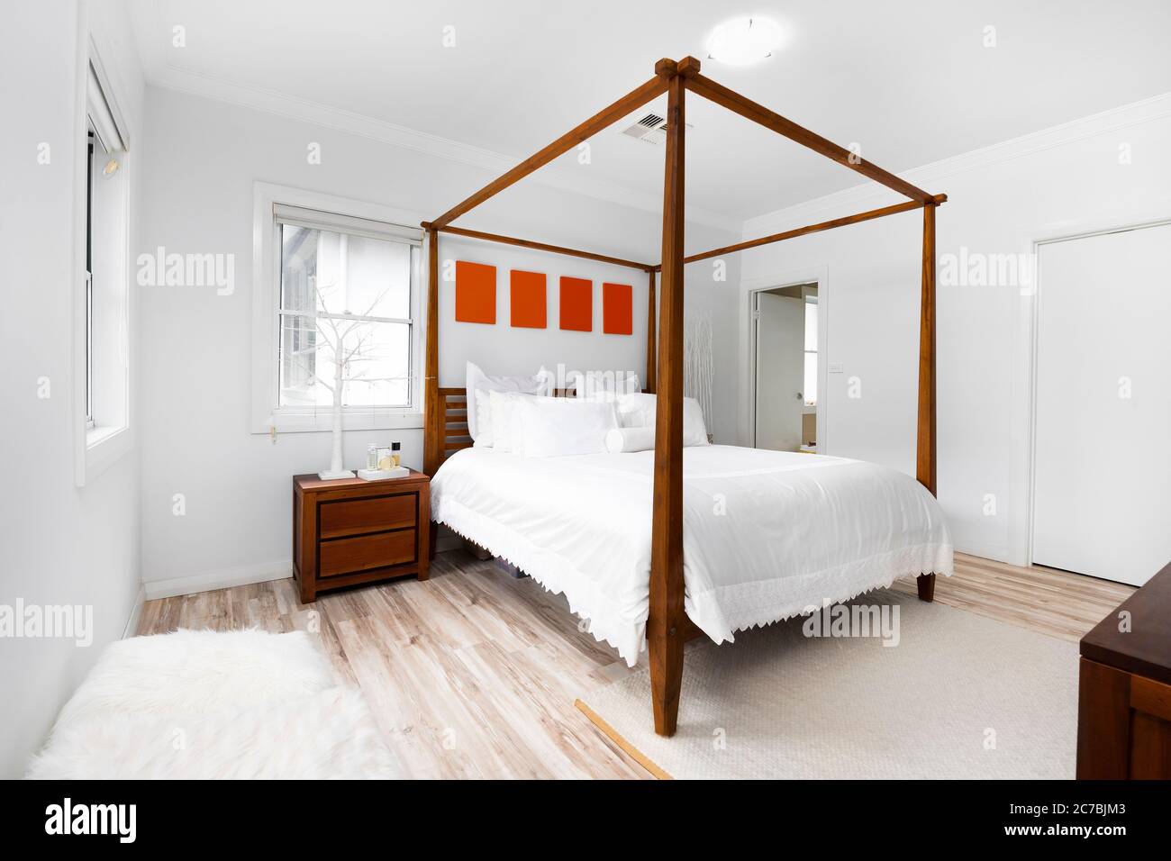Bright and cozy modern bedroom with en suite, large windows and cushions. Stock Photo